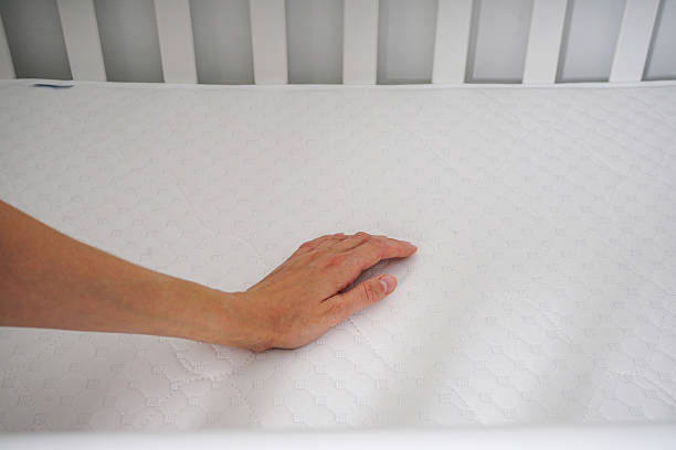 istock Young woman�s hands putting fitted sheet on baby crib mattress. 2229784000