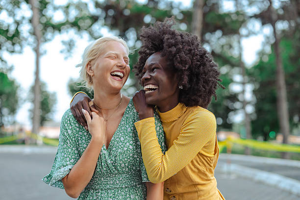 istock Two friends laughing together outdoors on a sunny day in a park 2229785545