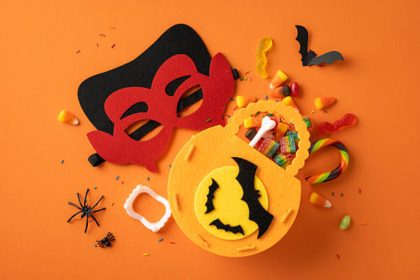 istock Vibrant Halloween setup featuring a colorful mask, candies, and themed decorations on orange 2229790826