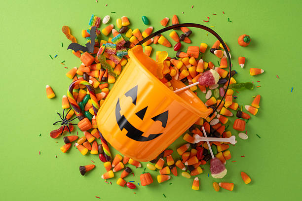 istock A Halloween-themed orange bucket in pumpkin shape surrounded by assorted candy on green 2229790832