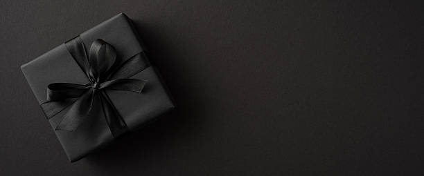 istock Elegant black gift box with a satin ribbon lying on a simple dark surface 2229790855