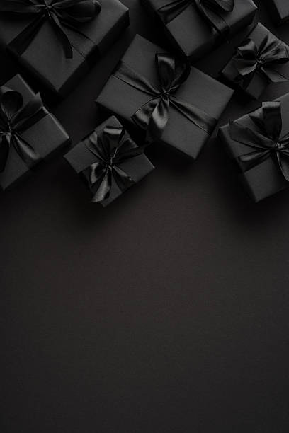istock Gift boxes wrapped in black paper with bows on a textured vertical dark background, creating a modern and sophisticated style 2229790859