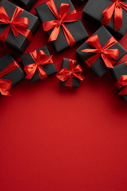 istock Elegant vertical black gift boxes adorned with red bows arranged on a bright red surface 2229790873
