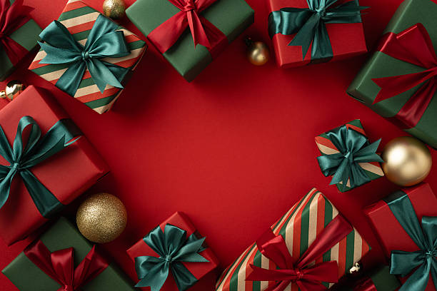 istock Gift boxes adorned with red and green wrapping paper and bows arranged festively on a red background 2229790907