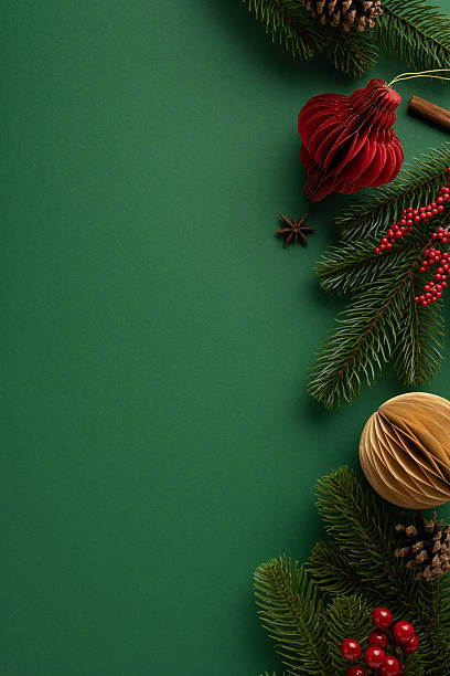 istock Festive vertical flat lay featuring evergreen branches, ornaments, and red berries on a green background 2229790930