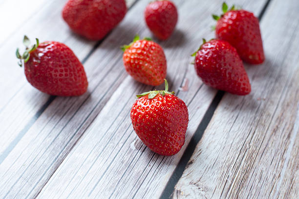 Several ripe strawberries are beautifully arranged on a wooden table