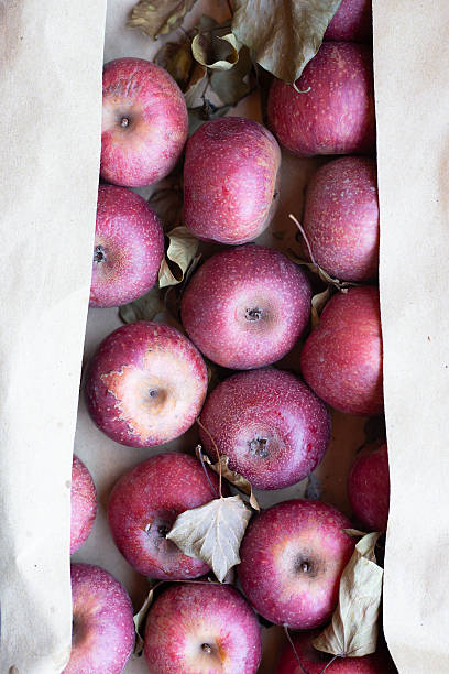 A beautifully arranged box filled with red apples, complete with leaves on them