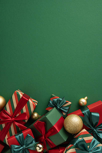 istock Several wrapped Christmas gift boxes with ornaments arranged on a green festive vertical table surface 2229793625