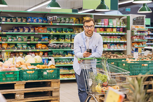 istock Customer using smartphone and shopping cart in supermarket 2229793645
