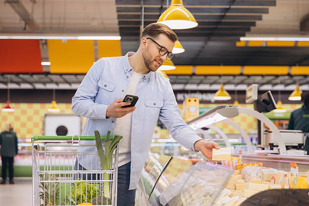 istock Man choosing cheese in supermarket using smartphone app 2229793776