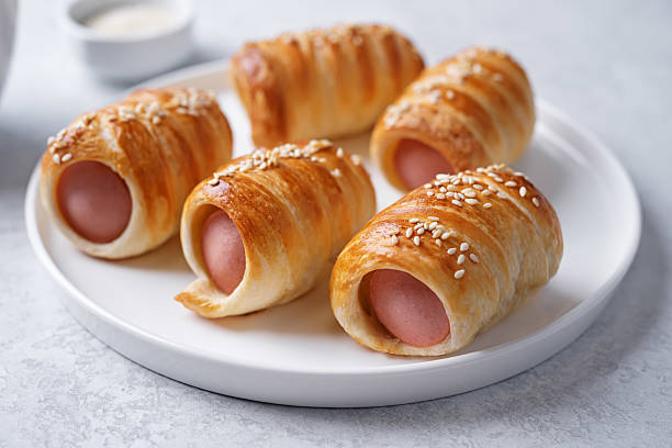 istock Sausage in dough, hot dog bread mini in a plate on a white background 2229796638