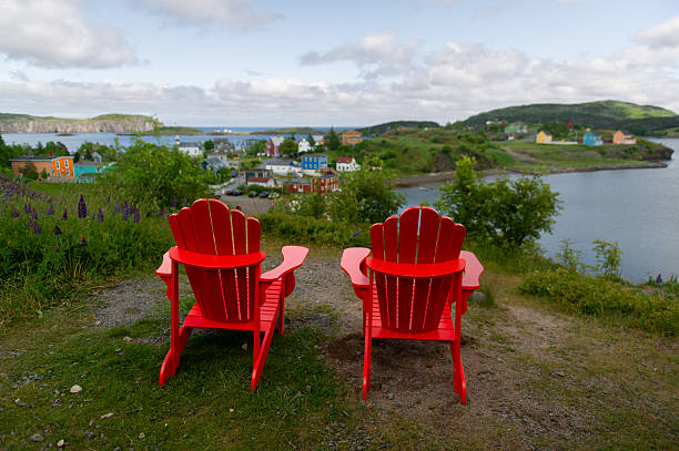 istock Two red Adirondack chairs on grassy bluff overlooking Trinity harbor 2229798696