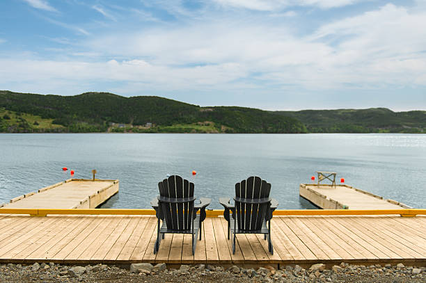 istock Two dark Adirondack chairs on wooden dock facing Trinity waters 2229798773