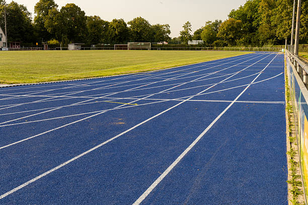 istock Blue running track at a stadium surrounded by green grass and trees, showcasing a vibrant athletic environment for outdoor sports activities 2229799078