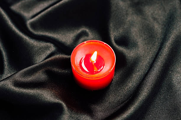 istock Red candle flame illuminates a dark fabric background creating a calming ambiance 2229799270