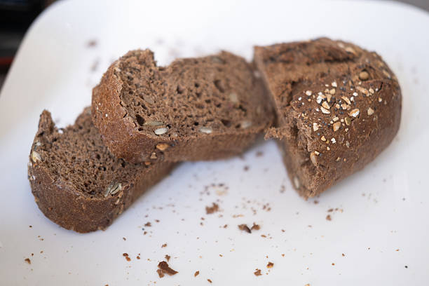 Close-up of sliced multigrain rye bread with seeds on white plate.