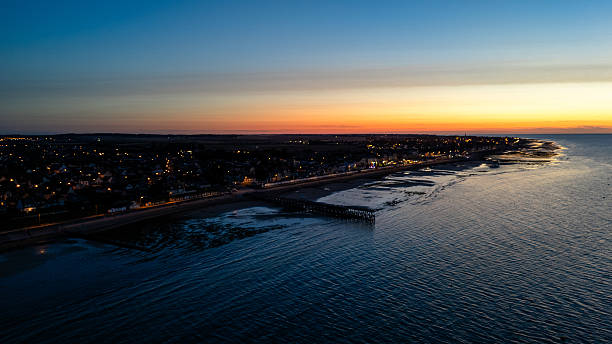 istock Coastal town dusk skyline with illuminated streets and sunset over water 2229806686