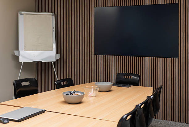 istock Modern conference room with table, chairs, flip chart and wall-mounted TV 2229807368