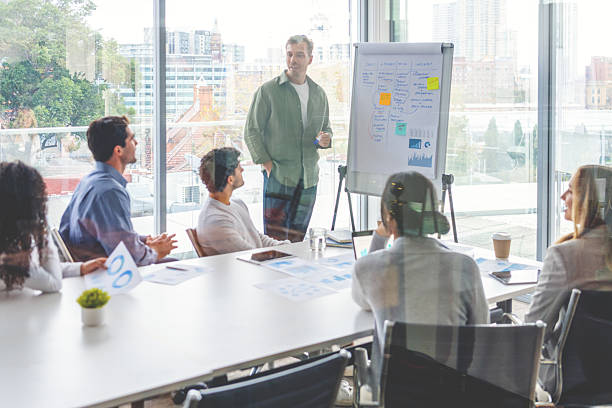istock Business people watching a presentation on the whiteboard. A man is writing on the whiteboard with charts and graphs. 2229807597