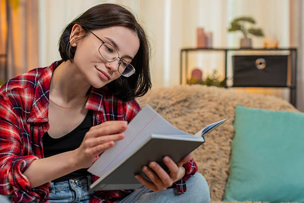 istock Young woman reading old journal notebook at home, smiling thoughtfully with soft nostalgic emotion 2229814629