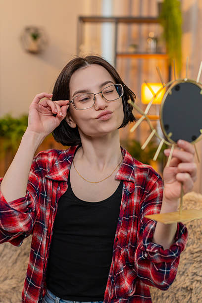 istock Young woman trying on new glasses at mirror, smiling while checking reflection with satisfaction 2229814670