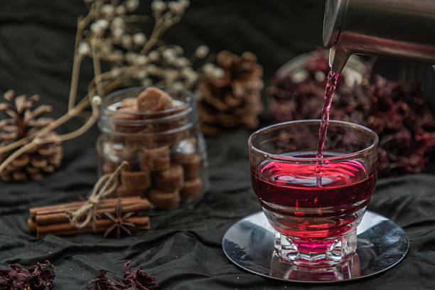 istock Roselle tea (Jamaica sorrel, Rozelle or hibiscus sabdariffa ) is poured from a kettle into glass cup  with dry roselle and brown cane sugar cube. 2229815142