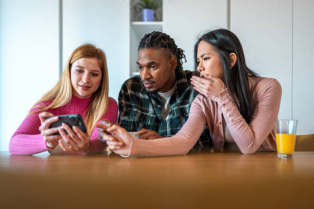 istock Diverse Mid Adult Friends Sharing Mobile Content While Relaxing At Dining Table 2229815987