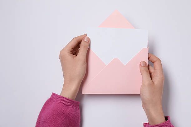 istock Woman holding letter envelope with card at white table, top view 2229823781