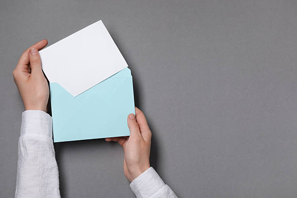 istock Woman taking card out of letter envelope at grey table, top view. Space for text 2229823854
