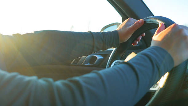 istock Hands gripping steering wheel of a car while driving under bright sunlight, showcasing focus and determination on the road ahead 2229824215