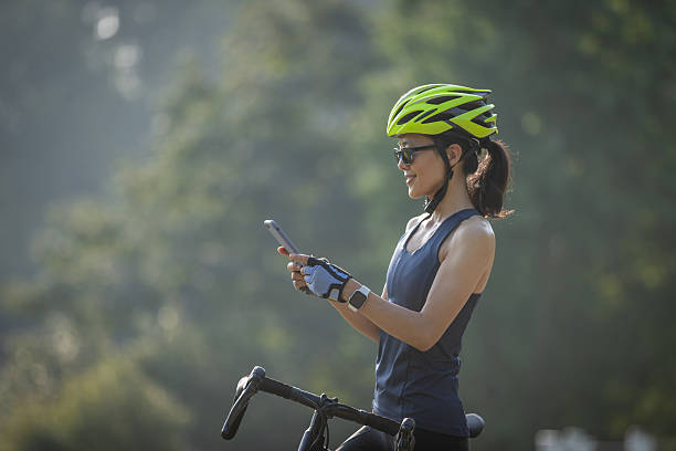 istock Woman cyclist using mobile phone in summer park 2229827945