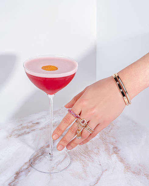 istock a woman's hand with gold rings reaches for a cocktail 2229828286