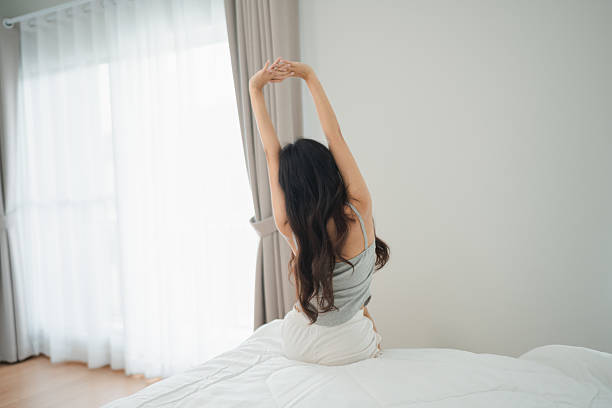 istock Woman Stretching on Bed in Bright Room with Natural Light, Morning Routine and Relaxation, Healthy Lifestyle Concept and Well-Being Atmosphere 2229836367