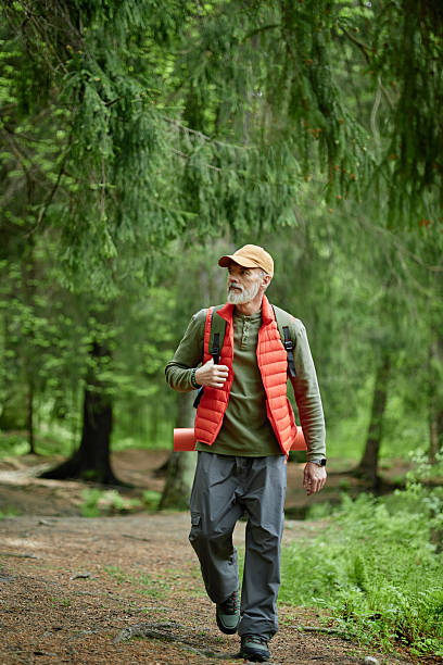 istock Senior Caucasian Man Hiking through Forest Carrying Backpack and Sleeping Mat 2229848068