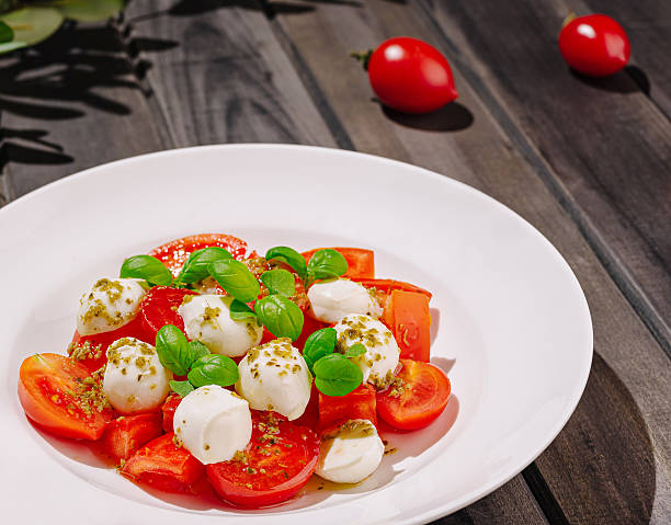 istock Fresh mozzarella and cherry tomato salad served on wooden table with herbs 2229854031