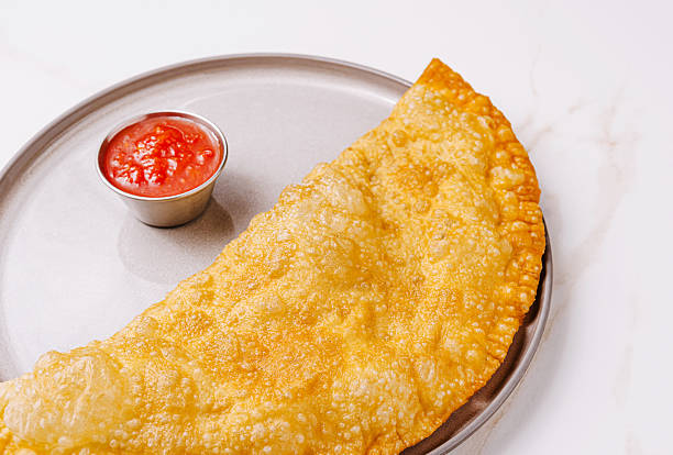 Savory crispy empanada served with tangy dipping sauce on a plate