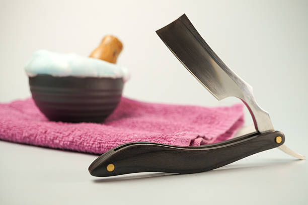 Shaving accessories including a straight razor, shaving soap, and pink towel evoke a sense of pampering and relaxation