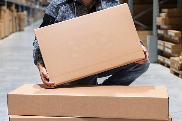 istock Warehouse Worker Lifting Cardboard Box for Inventory and Shipment Preparation Process 2229859956