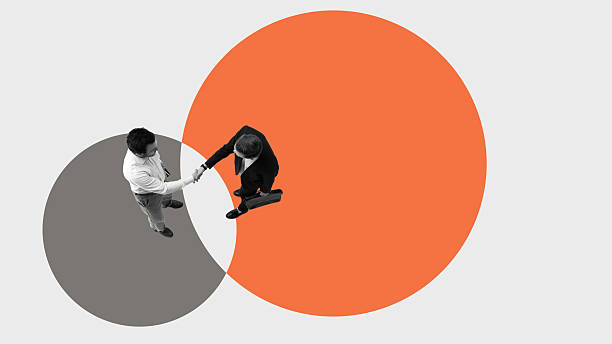 Conceptual artwork of businessmen shaking hands in intersecting circles symbolizing merger integration