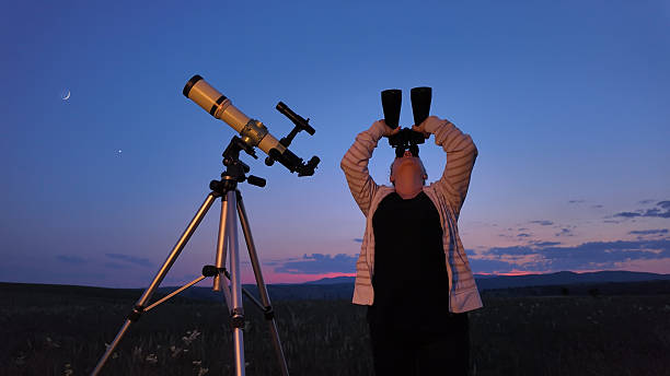istock Amateur astronomer using telescope and binoculars  for watching stars, Moon, planets and other celestial objects from a countryside field in nature. 2229870903