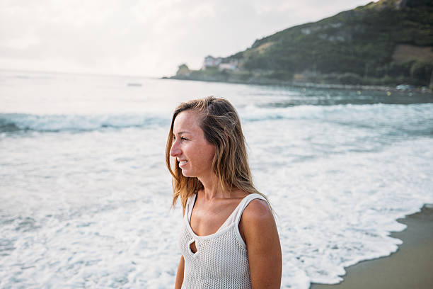 istock Happy young woman walking on empty beach at sunrise 2229878973