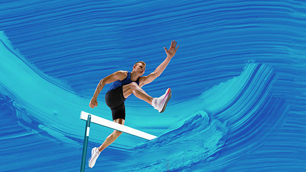 istock Creative artwork. Male athlete leaping over hurdle with focused expression on dynamic blue paint stroke background 2229879581