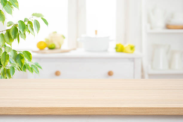 istock Beige wooden table for product presentation over blur kitchen interior background and green plant leaves 2229881792