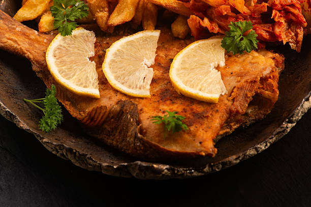 Baked fish with lemon and herbs, top view.