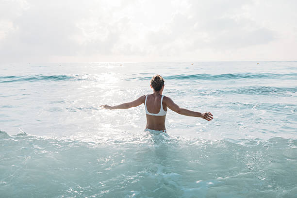 istock Woman Walking Into Calm Ocean Water 2229887391