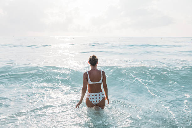 istock Woman Walking Into Calm Ocean Water 2229887392