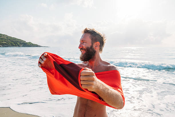 istock Man Taking Off Shirt on Sunny Beach Shore 2229888047