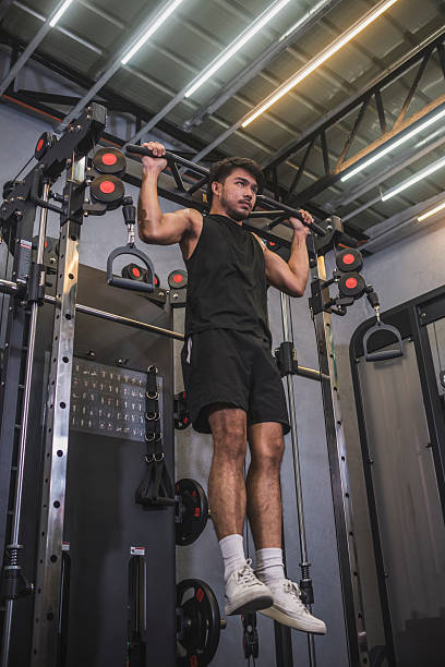 istock Intense workout scene as a fit Asian man engages in behind the neck pull-ups at a well-equipped gym, showcasing strength and dedication. 2229890259