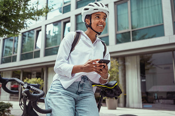 istock Young Multiracial Woman Using Smartphone While Cycling in Business District 2229897023