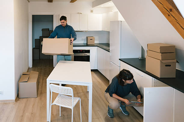 istock Relocation: A young woman checks the kitchen cabinets with a touchpad while a man packs boxes 2229900635